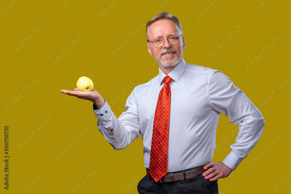 Portrait of handsome senior man posing to the camera. Male is holding an apple in hand. Isolated ove