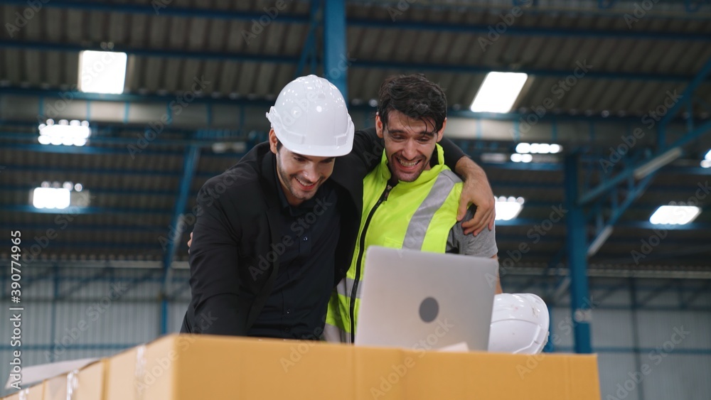 Two factory worker celebrate success together in the factory or warehouse . Industry work achievemen