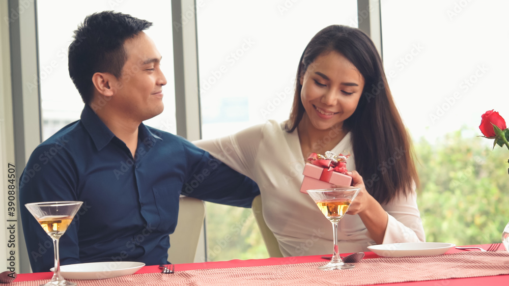 Romantic couple giving gift to lover at restaurant . Happy couple lifestyle .