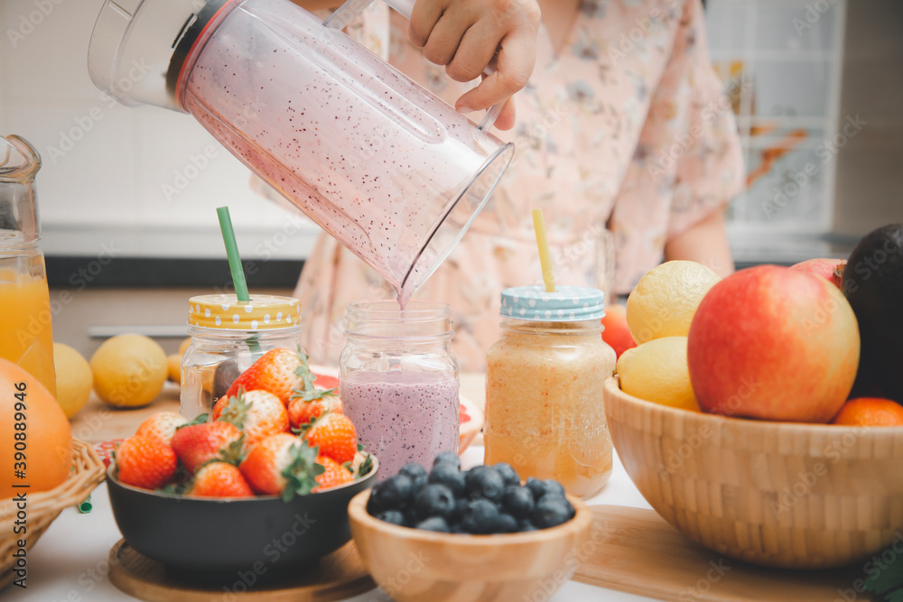 Happy woman enjoy preparing freshly squeezed fruits with vegetables for making smoothies for breakfa