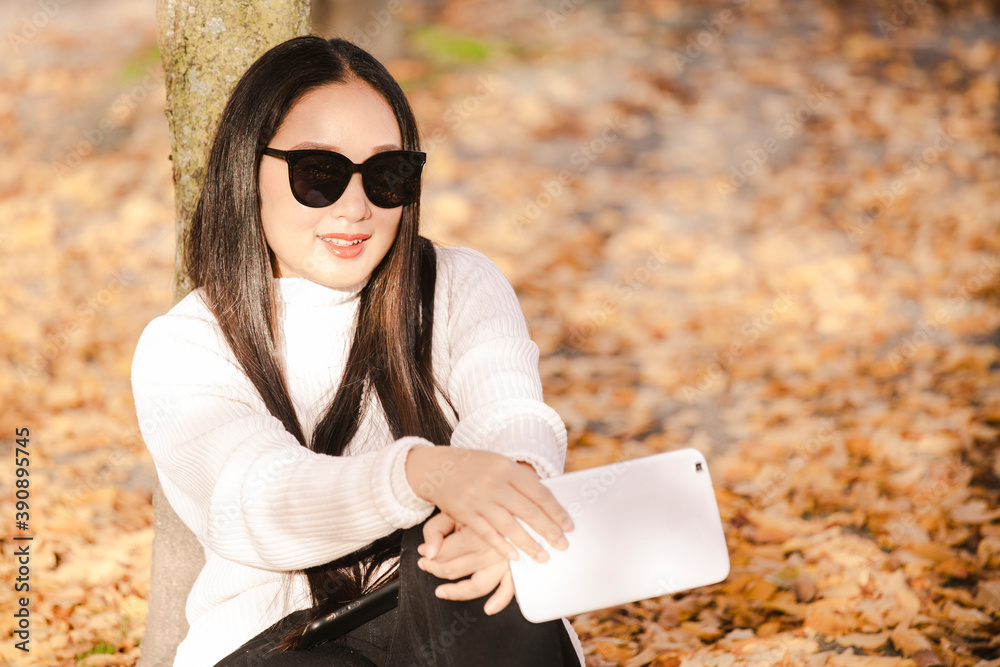 Asian beautiful woman is travel for holiday in the winter of Europe and view autumn leaves of big tr