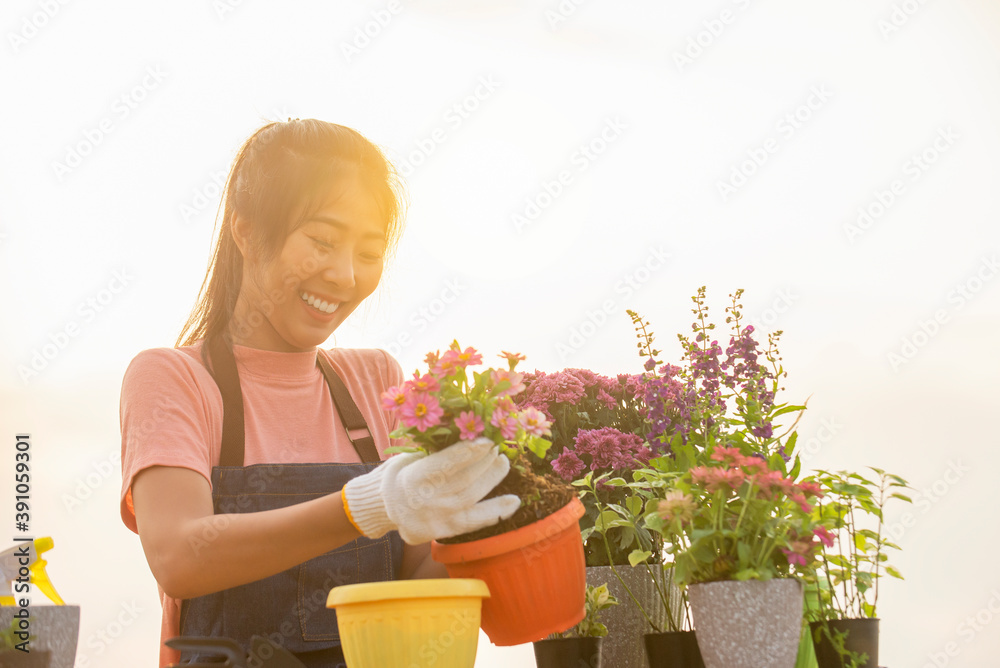 戴着手套的亚洲年轻女子在户外花园里种花