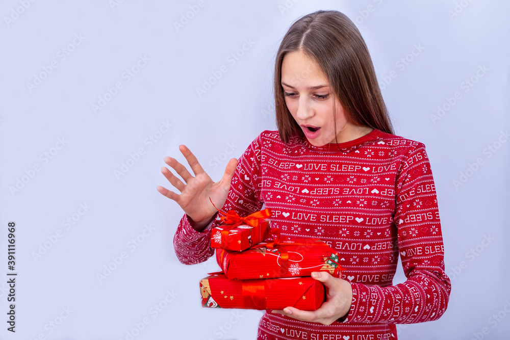 Young caucasian girl with bow ribboned boxes in hands is happy with gifts. Emotional girl stands in 