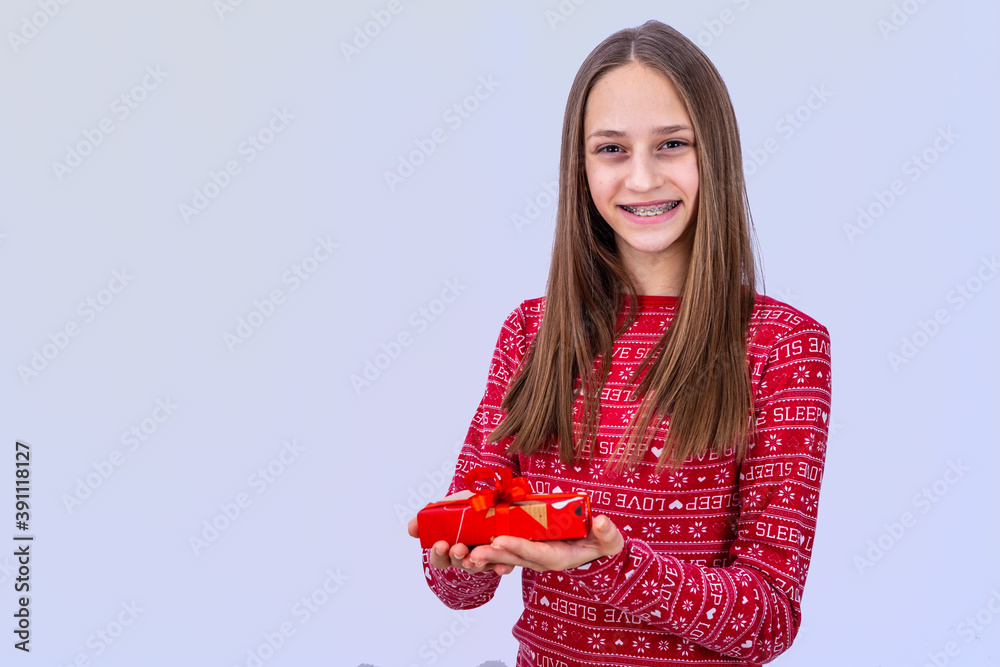 Young caucasian girl with dental braces is smiling. Emotional girl holding gifts and showing incredi