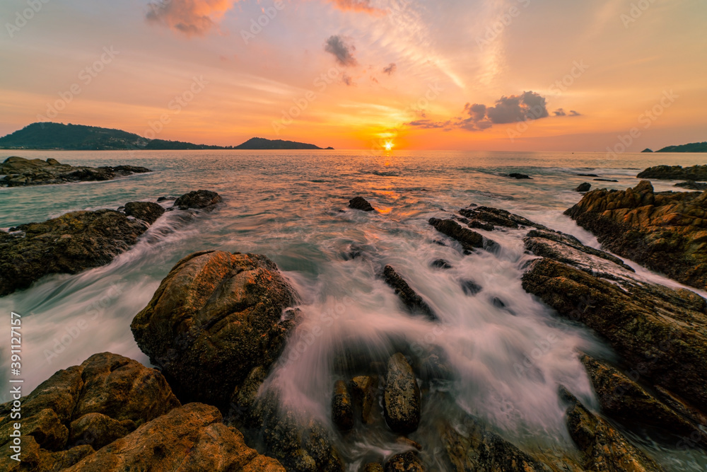 戏剧性的天空海景的长曝光图像，前景是日落或海上日出时的岩石