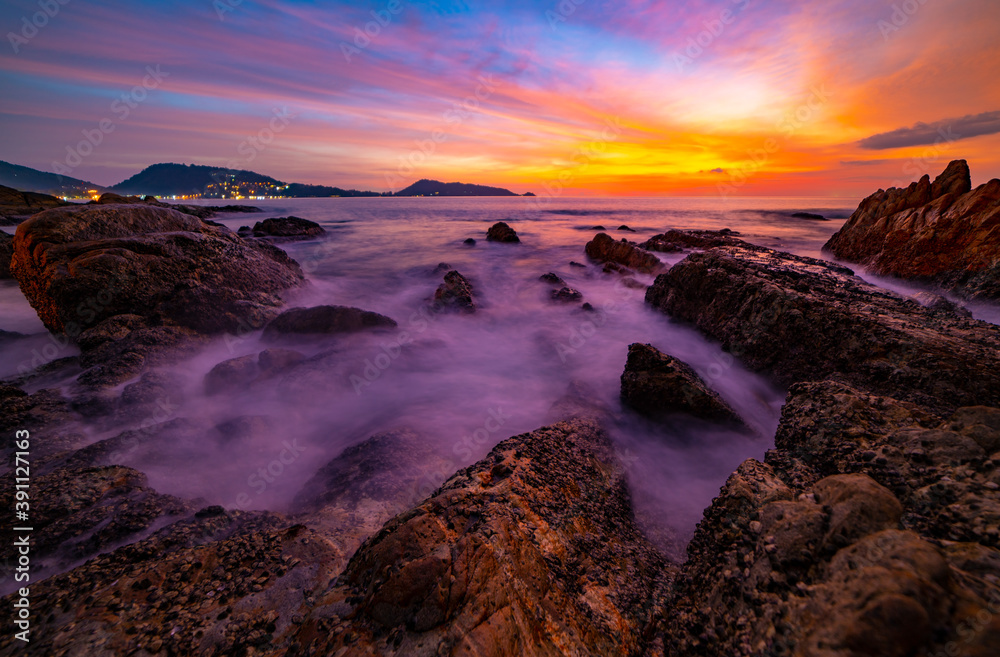 戏剧性的天空海景的长曝光图像，前景是日落或海上日出时的岩石