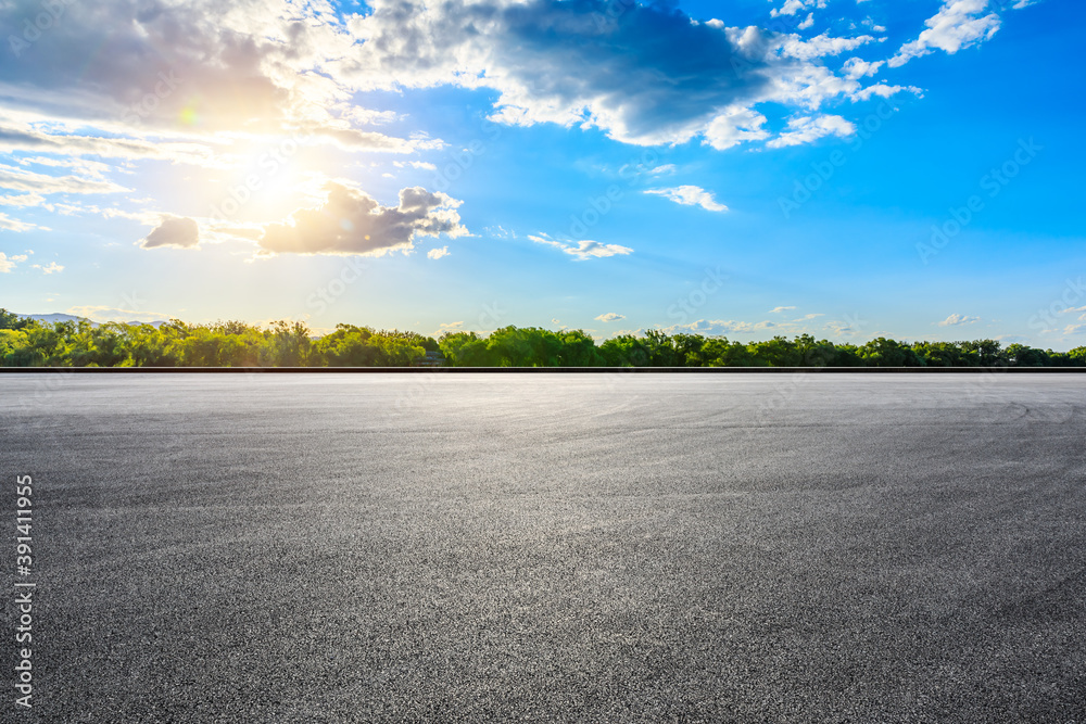 Empty asphalt road and green forest at sunset.