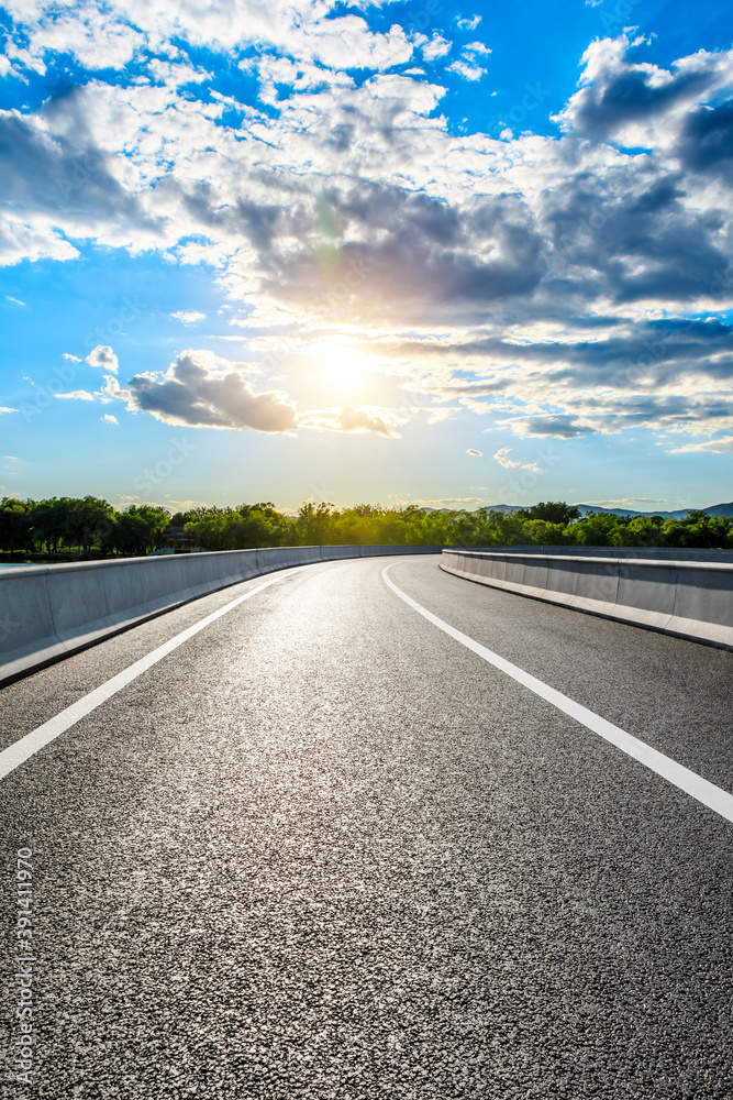 Empty asphalt road and mountain with forest landscape at sunset.