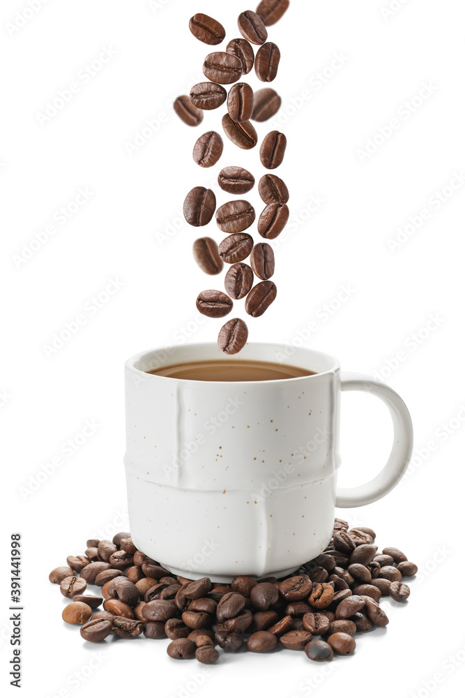 Cup of hot drink and falling roasted coffee beans on white background