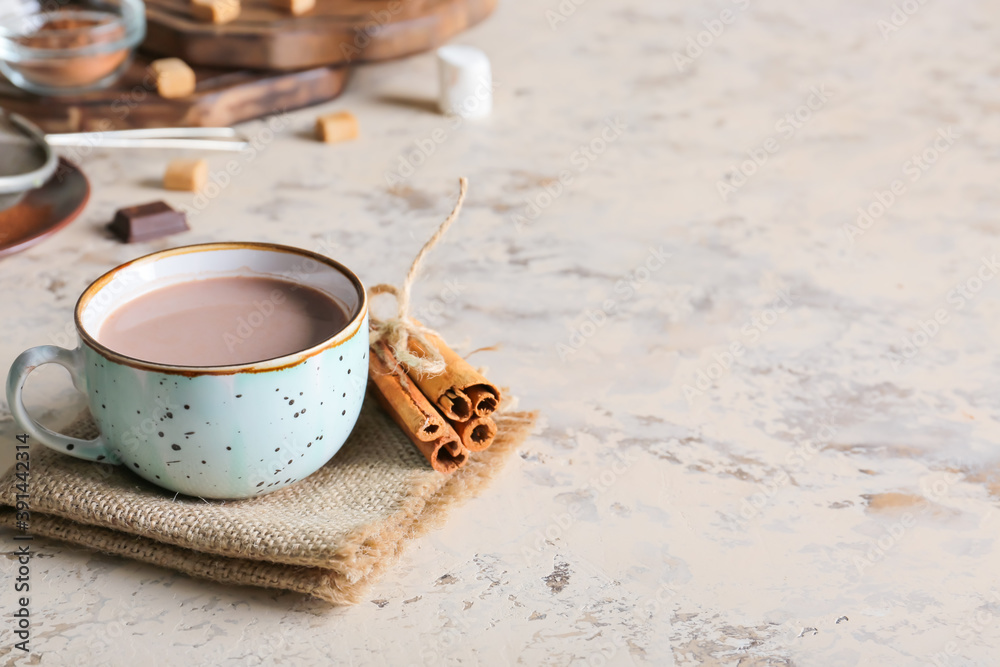 Cup of hot cacao drink with cinnamon on grey background