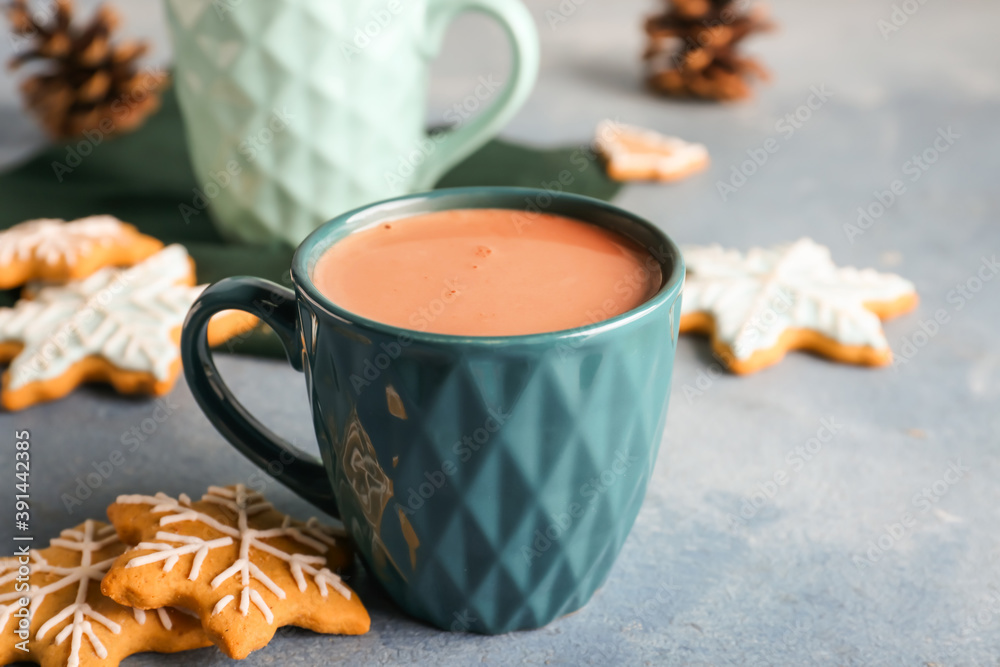 Cup of hot cacao drink with cookies on color background