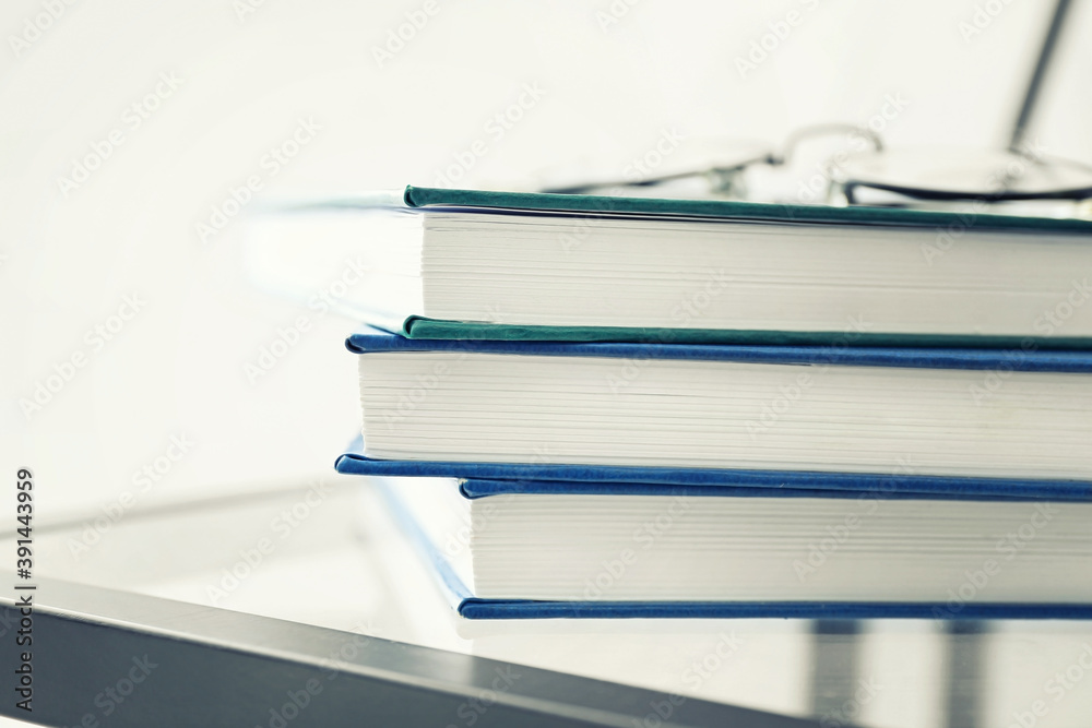 Stack of books and glasses on table, closeup