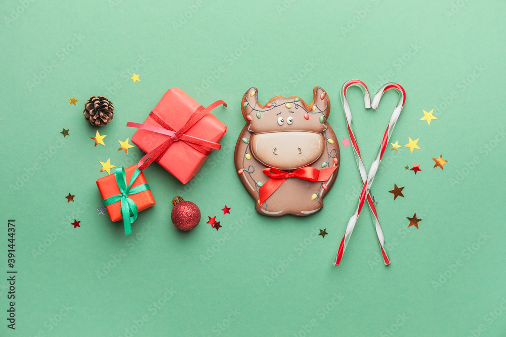 Tasty cookie in shape of bull and Christmas decor on color background