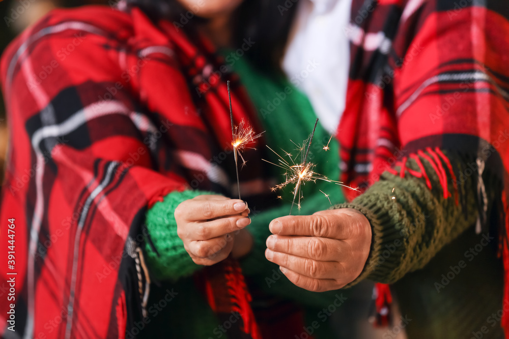 Mature couple with sparklers celebrating Christmas at home, closeup