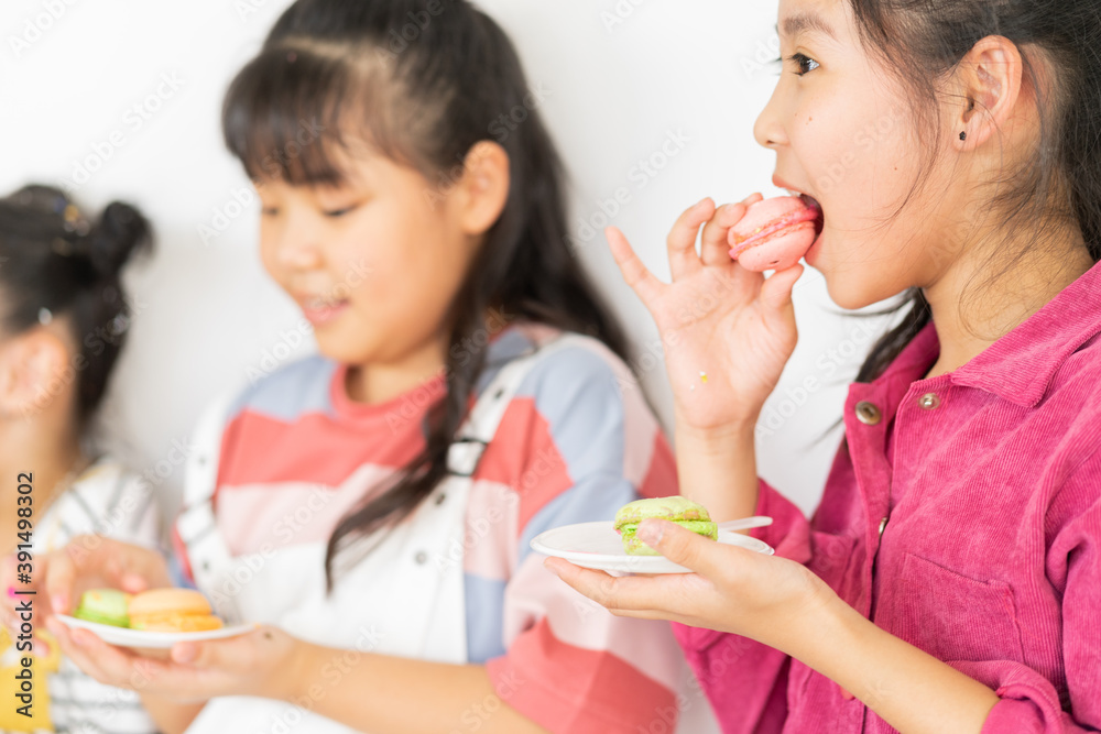 The little girl is eating cake with her friends
