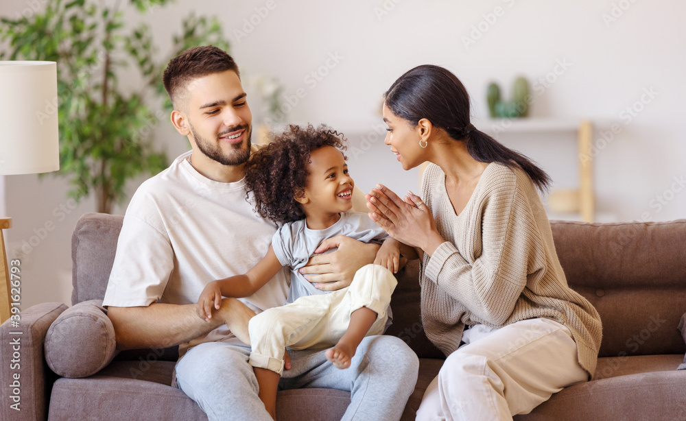 happy multi ethnic family mother father and son having fun at home on couch 