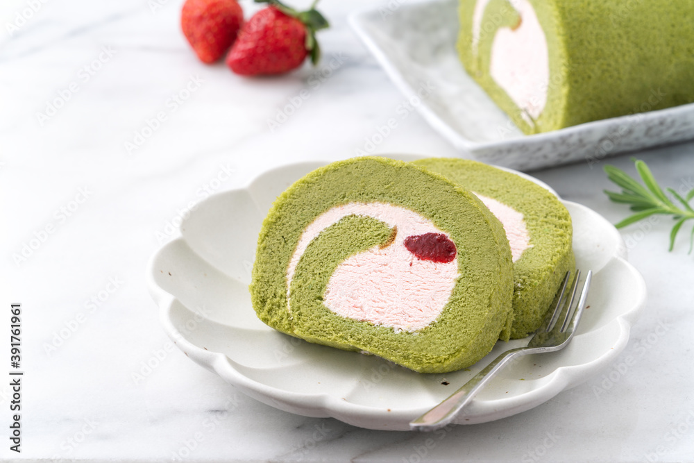 Delicious Matcha Swiss Roll Cake slices with strawberry cream on white background.