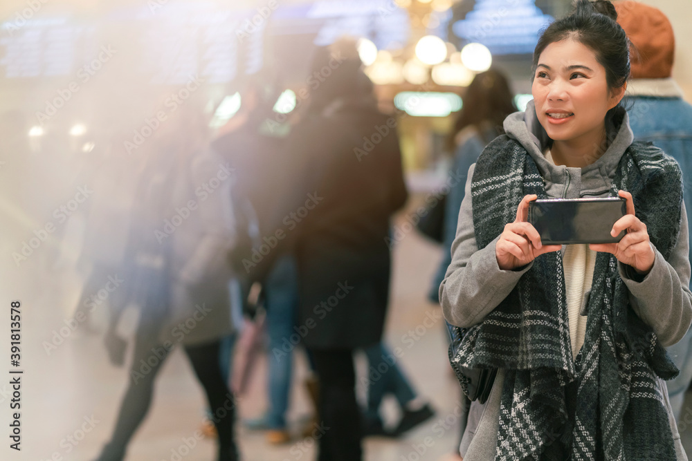 年轻的亚洲女性旅行者观光并享受先进时刻，手持智能手机拍照