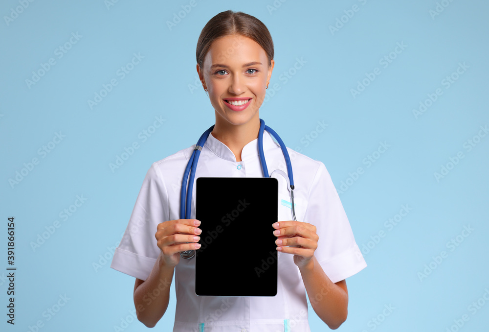 friendly doctor nurse with tablet wireless computer smiles in isolated against   blue background.