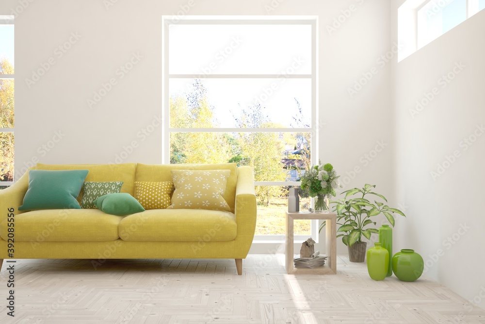 Stylish room in white color with sofa and autumn landscape in window. Scandinavian interior design. 