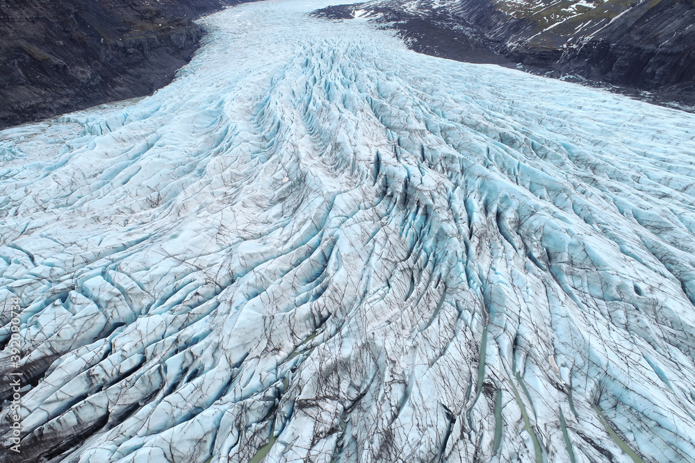 Beautiful glaciers flow through the mountains in Iceland. Aerial view and top view.