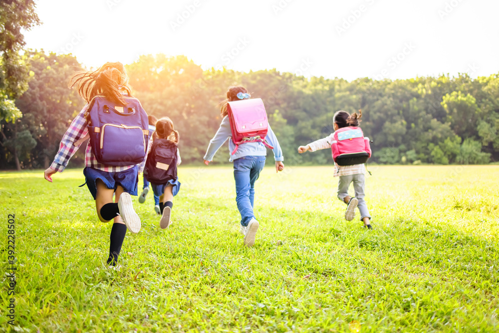 小学生在草地上奔跑的后视图