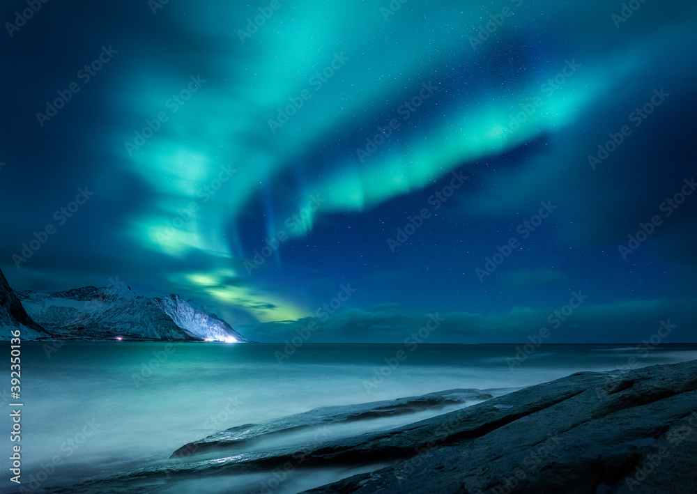 Aurora borealis in Norway. Green northern lights above mountains and ocean. Night winter landscape w