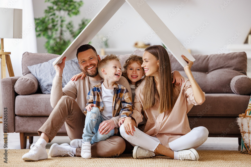 concept housing  young family. mother father and children under fake roof in  new home.