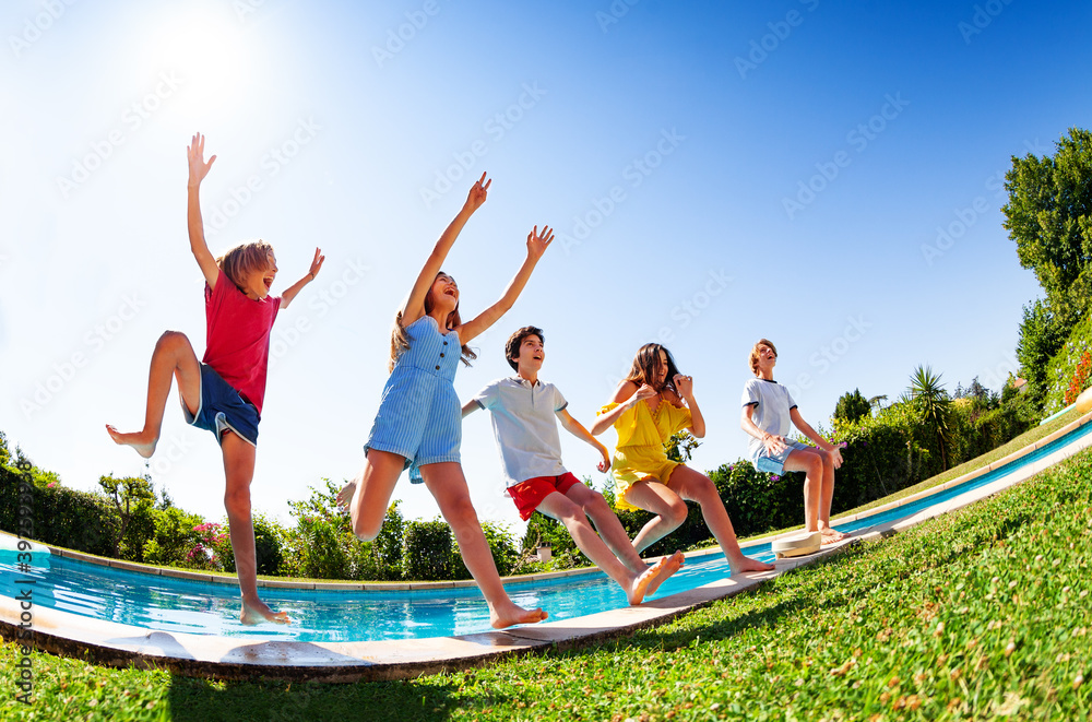 View from bellow of Group of happy teen children in mid air fall into pool water hands up laughing a