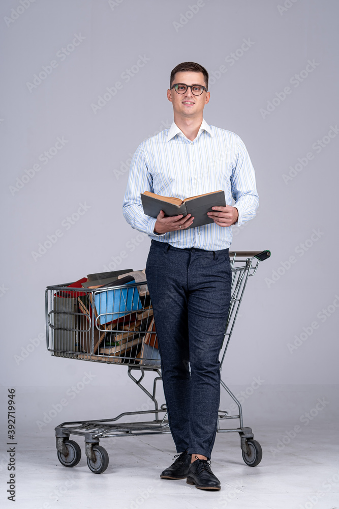 Young man in white shirt with pile of books in pushcart. Achieving results for future profession. Di