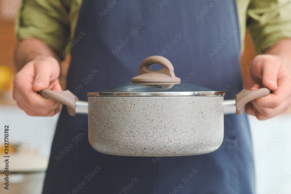 Man with cooking pot in kitchen, closeup