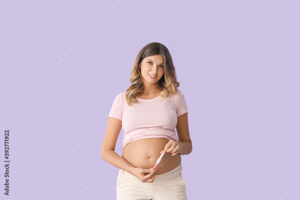 Beautiful pregnant woman with test on color background