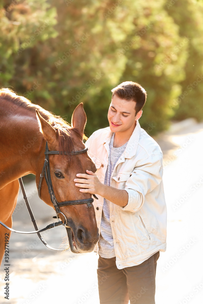 Young man with cute horse outdoors