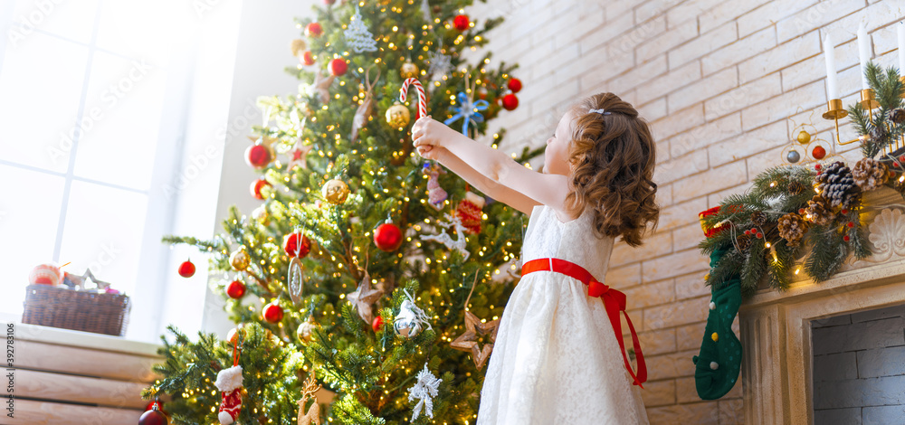 girl is decorating Christmas tree