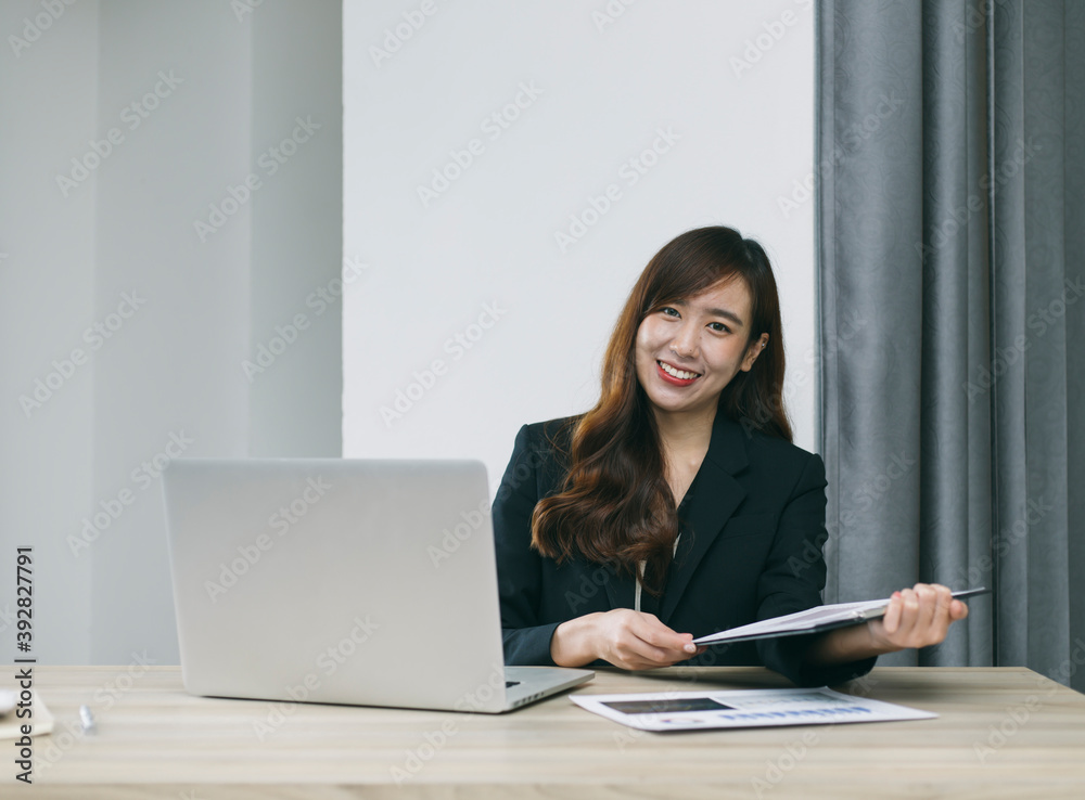 一位女商人坐在电脑桌上，手里拿着一份纸质计划、商业计划、在家工作的秘密