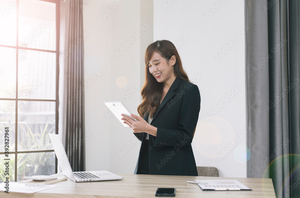 一位年轻的亚洲女商人在下班后的晚上，在现代化的办公室窗户旁接受商业想法