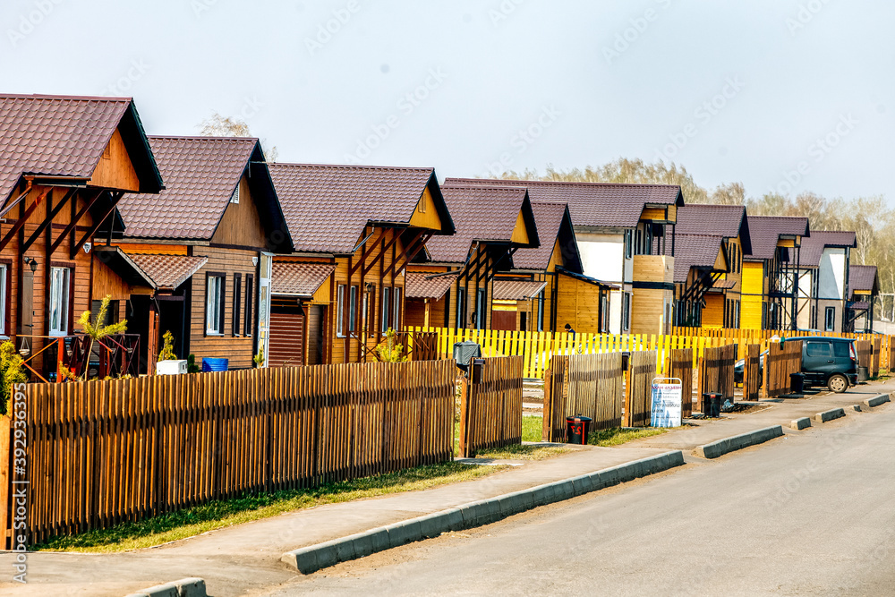 Wooden houses residental community made in one-style with dark-brown color roofs.