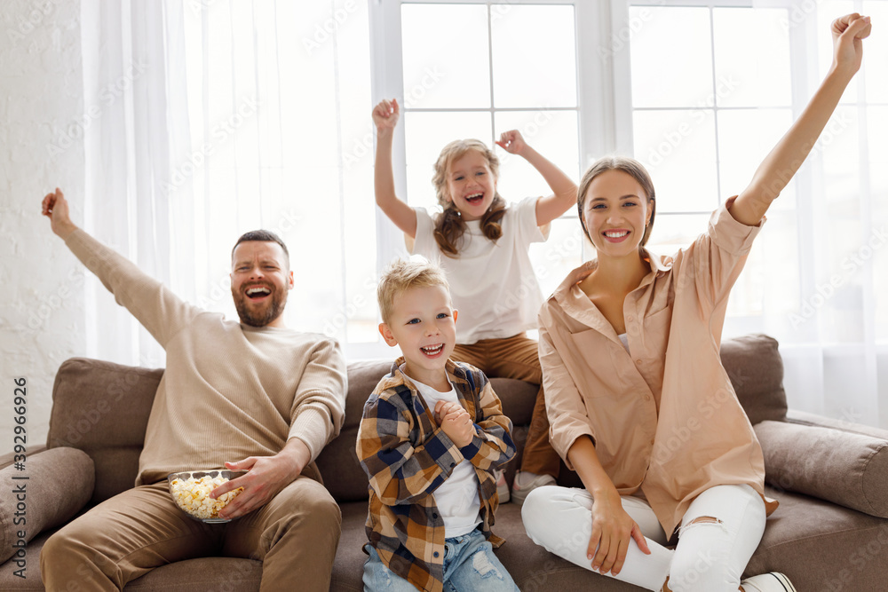 Family celebrating goal on sofa.