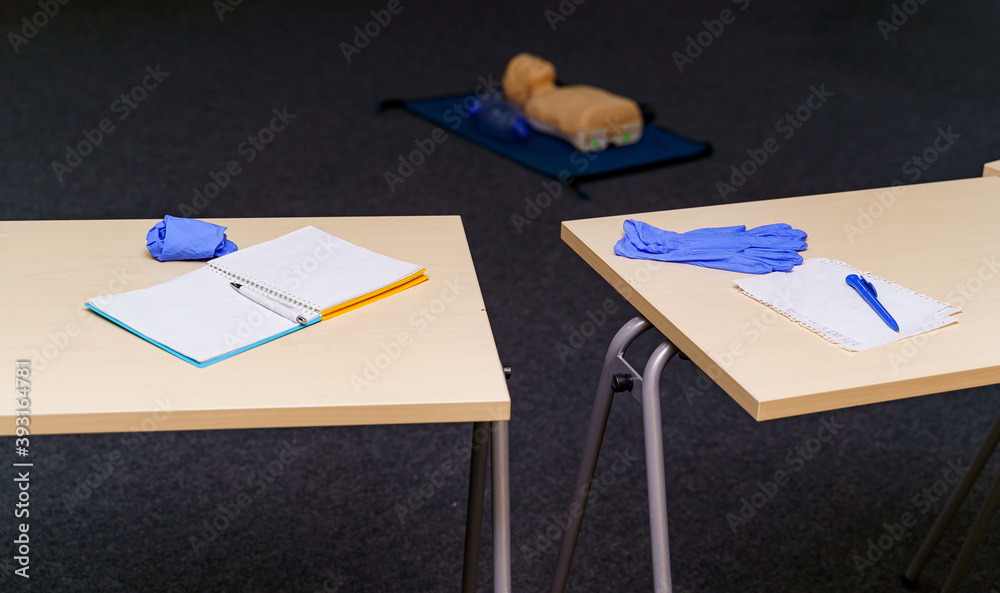 Pens and notepads on the wooden desks. Training concept. Life saving education. Medical dummy on the