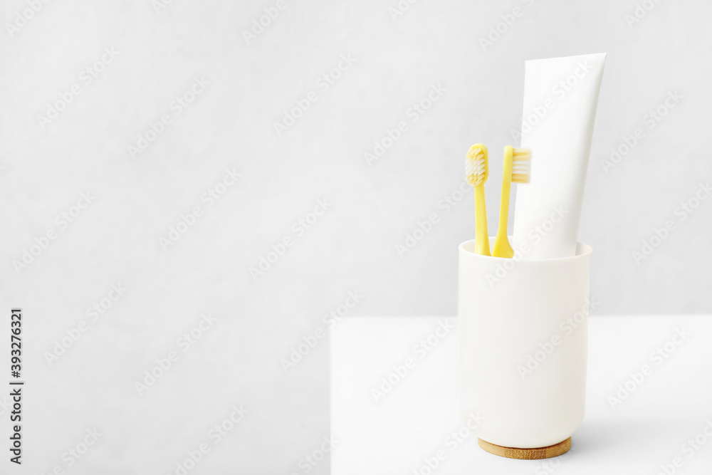 Holder with toothbrushes and paste on table