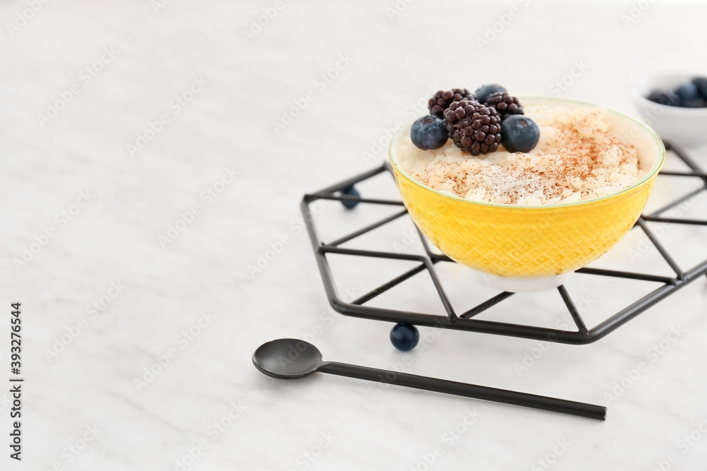 Bowl of tasty rice pudding with berries on white table