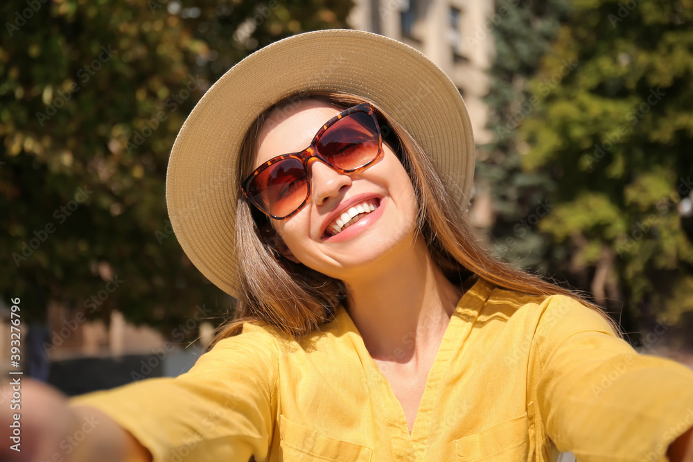 Beautiful young woman taking selfie in park