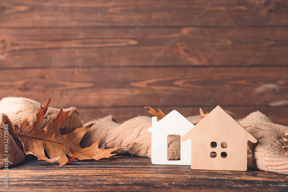 Figures of house, autumn leaves and warm scarf on table. Concept of heating season