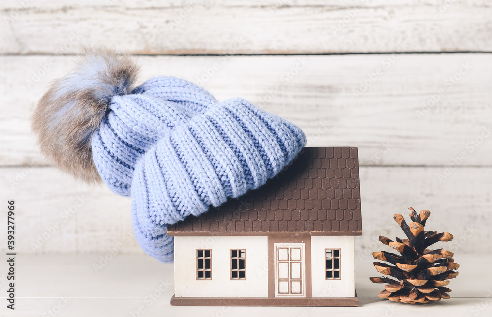 Figure of house and warm hat on table. Concept of heating season