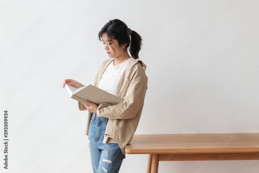 Asian woman leaning on a wooden table while reading a book