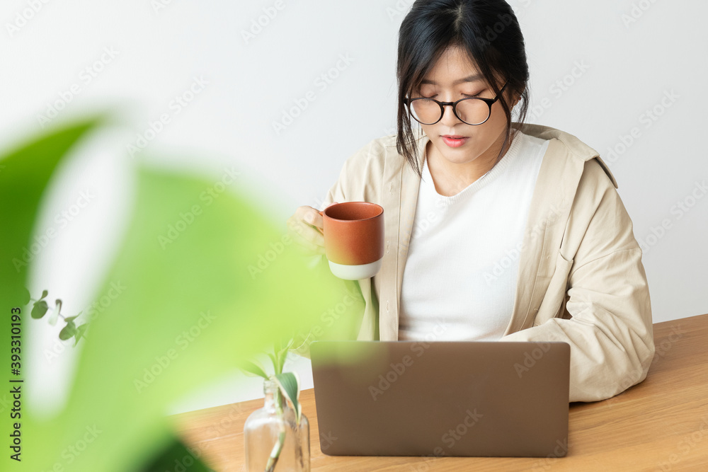 Asian woman drinking coffee while working at home