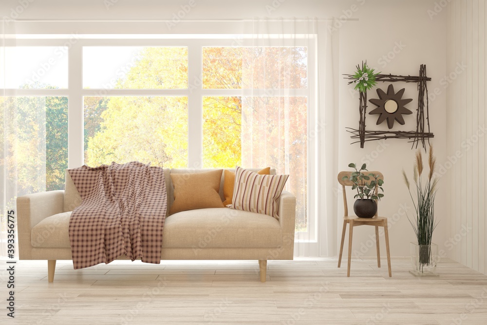 Stylish room in white color with sofa and autumn landscape in window. Scandinavian interior design. 