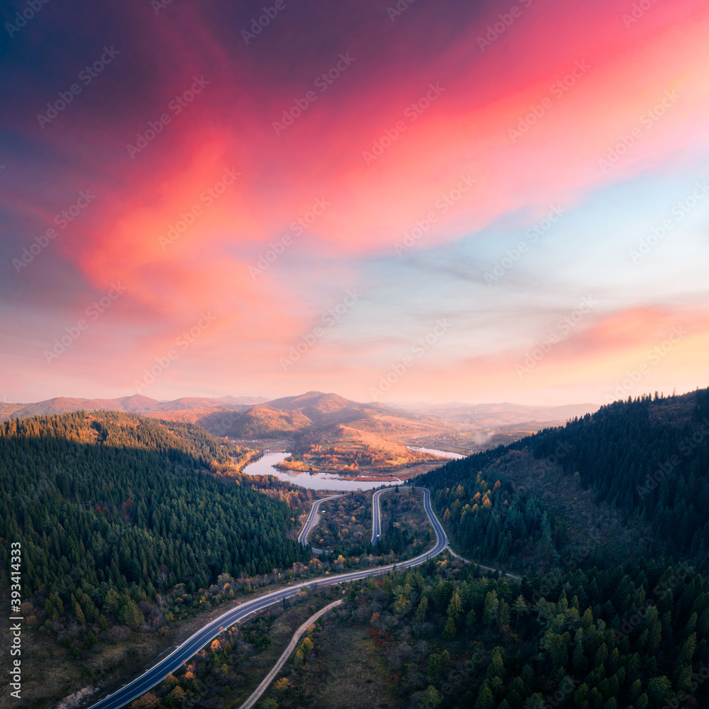 Aerial drone view over the autumn mountains with mountain road serpentine, river and forest. Landsca