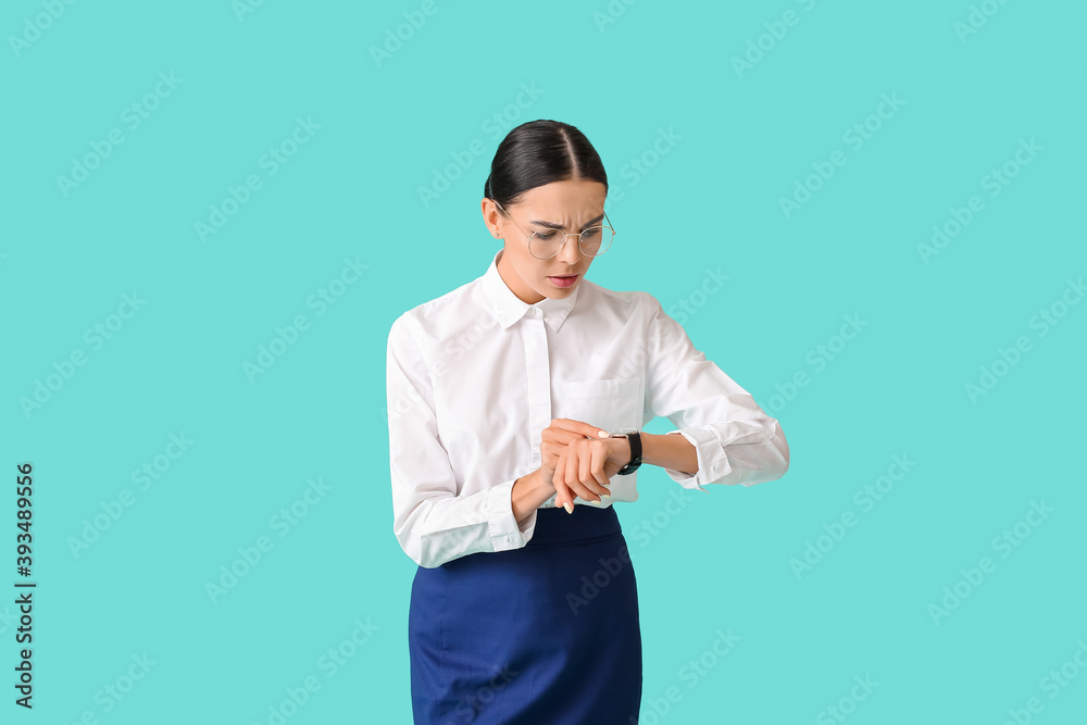 Businesswoman looking at watch on color background