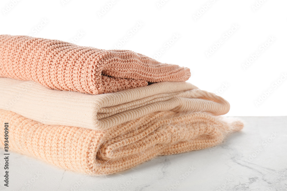 Stylish winter clothes on table against white background